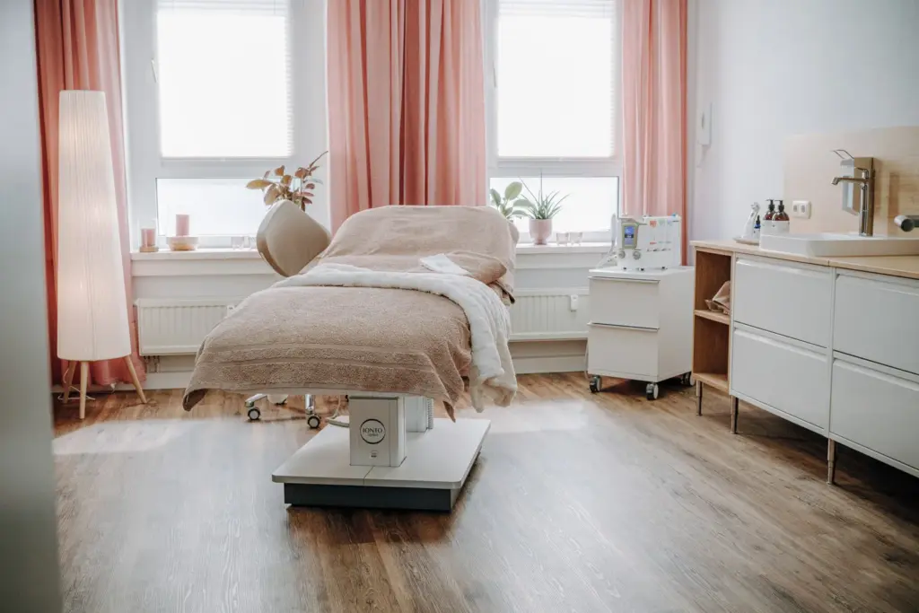 Behandlungsraum mit Liege, Waschbereich und warmen Farbtönen im Skincare Studio Alexandra Linsner