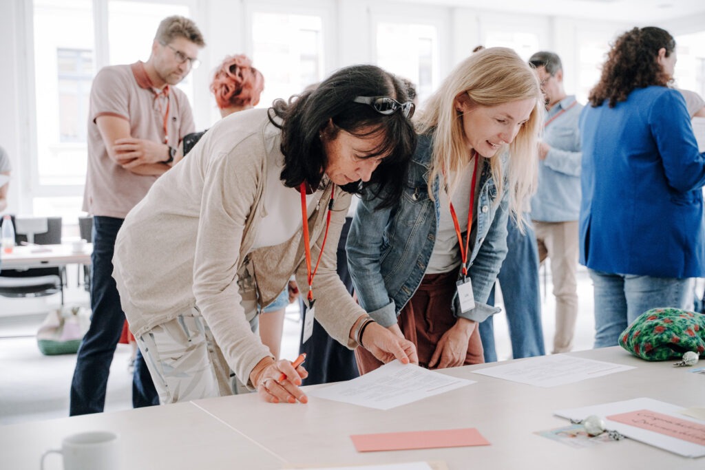 Teilnehmerinnen bearbeiten Unterlagen beim Workshop des Bundesnetzwerktreffens in Meerane