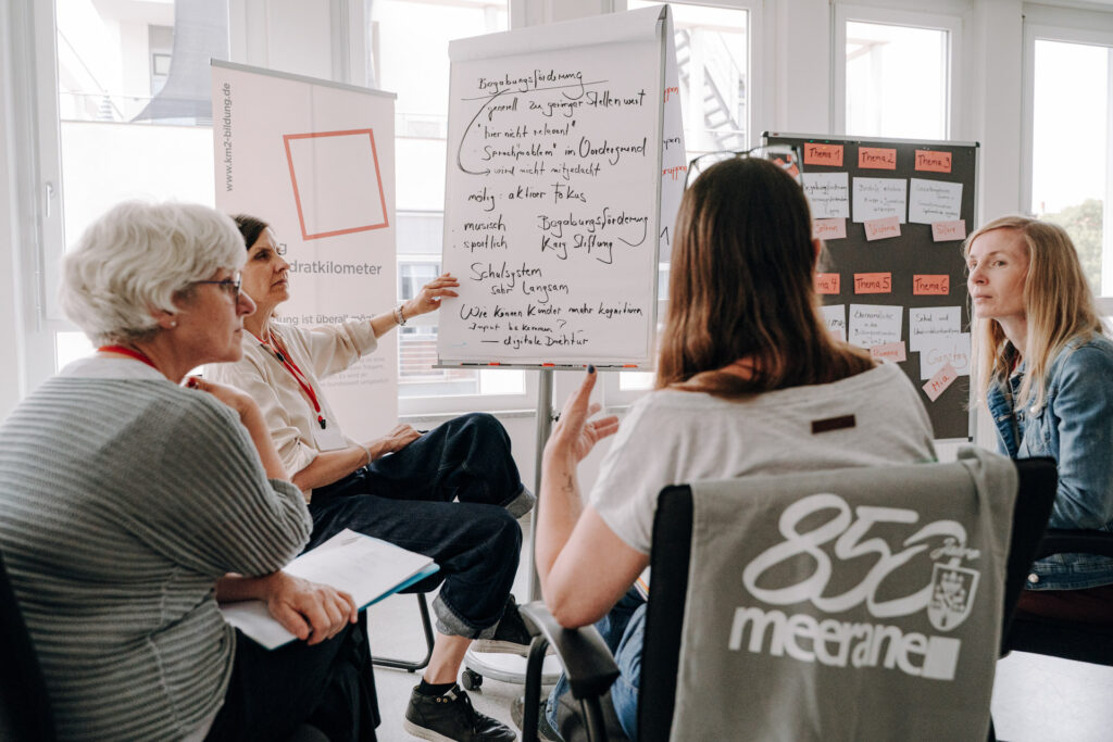 Teilnehmende besprechen Workshop-Ergebnisse auf einem Flipchart beim Bundesnetzwerktreffen in Meerane